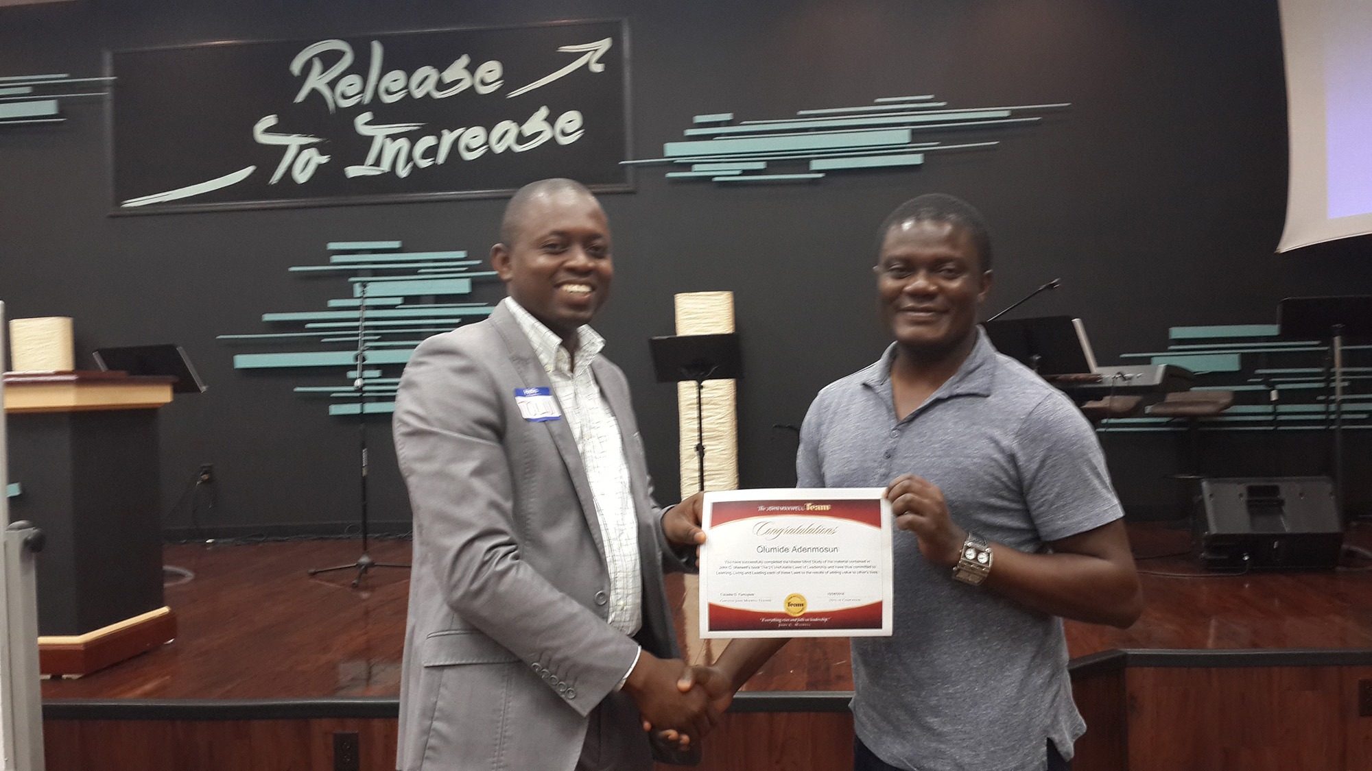 Two men shaking hands while holding a certificate